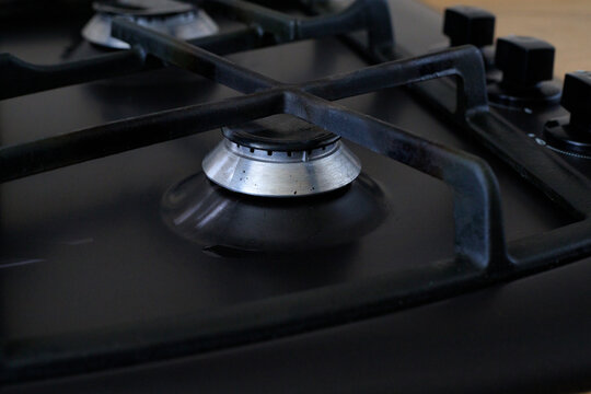 Turned off gas stove burner. Empty black metal trivet grate on a kitchen cooktop hob surface without fire. Domestic household appliance
