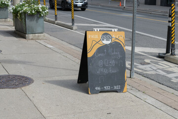 Fototapeta premium a-frame chalkboard sign outside Paul Hahn & Co, a piano store, located at 1058 Yonge St, Toronto