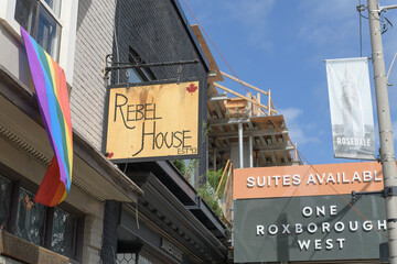 Fototapeta premium projecting sign outside The Rebel House and construction site signage at One Roxborough West, Toronto