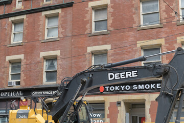 Fototapeta premium construction work at College St near Yonge in Toronto featuring Deere heavy equipment and Tokyo Smoke Cannabis (450 Yonge St)