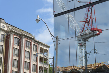 Fototapeta premium view of building at 2 Roxborough St E (left) and mirrored window facade of 1027 Yonge St with reflection of a crane at a construction site (One Roxborough West), Toronto