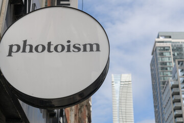 Fototapeta premium wall-mounted round projecting sign outside Photoism Downtown Wellesley, a photo booth, located at 584 Yonge St, Toronto