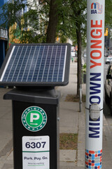 Fototapeta premium Municipal Parking solar-powered pay-and-display machine and pole banners in the Midtown Yonge area of Toronto
