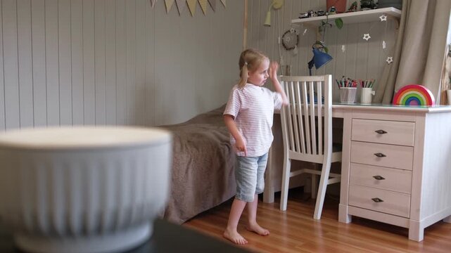 Smart speaker on table playing music for dancing little girl on blurred background. Cute child listening to audio voice assistant in bedroom. Modern smart home, AI technology and lifestyle concept.