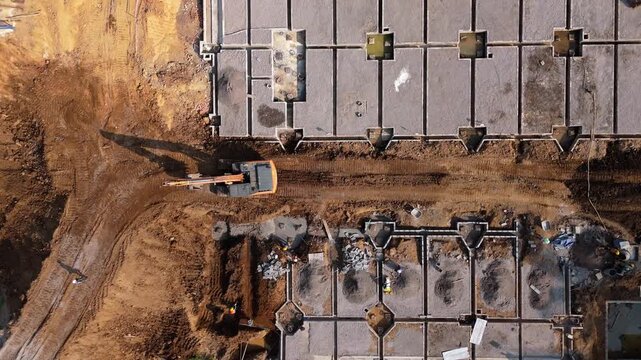 Aerial view of heavy-duty excavator working on the foundation of a new building project in Mungkid, Central Java, Indonesia.