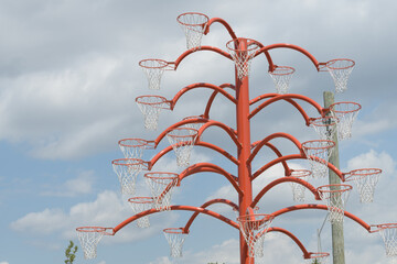 Fototapeta premium view of Alexandre Arrechea's Orange Functional, 2022, composed of steel and basketball nets, #1, in the plaza of Old Firehall 30, at Biidaasige Park, Port Lands, Toronto