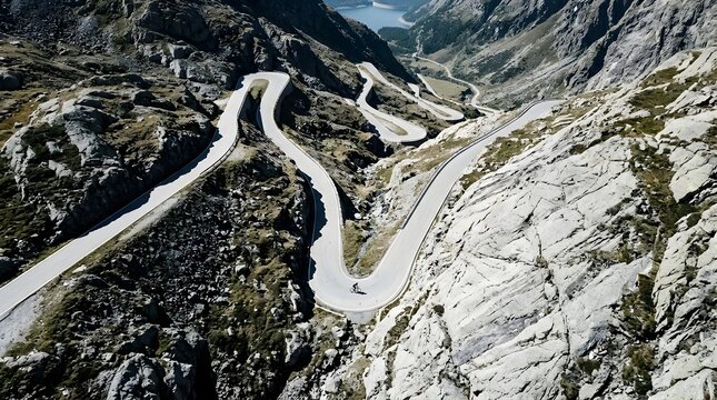 Aerial view of a cyclist on a winding mountain road in the Swiss Alps