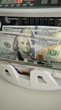Counting American dollars in a money counter machine at a bank office in broad daylight
