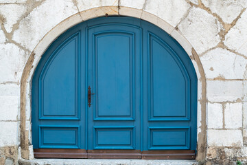 Fototapeta premium elegant arched blue wooden door set into an ancient stone wall in the historic medieval town