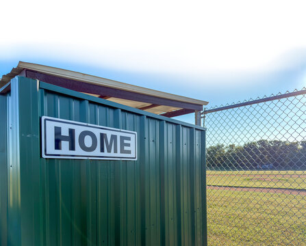 Home bench for a Away Team little league team next to a baseball diamond with a transparent sky
