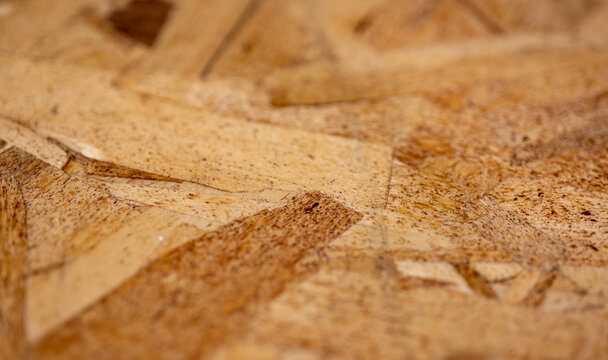 Macro of light brown OSB particle board  with softly focused foreground and background
