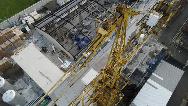 Aerial view of a construction site with a yellow tower crane and building materials on a rooftop in Purwokerto, Central Java, Indonesia.