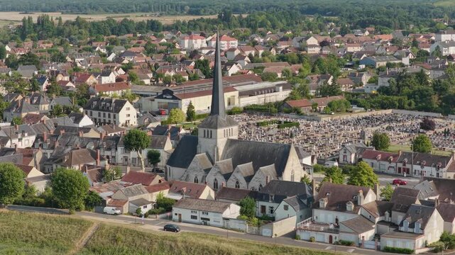 High-resolution aerial footage showcasing the historic church with a tall spire at the center of Sully-sur-Loire, France.