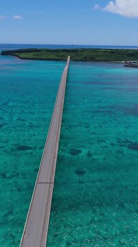 Vertical aerial footage dollying forward with a slight downward tilt above Kurima Bridge leading toward Yonaha Maehama Beach on Miyako Island, Okinawa, Japan
