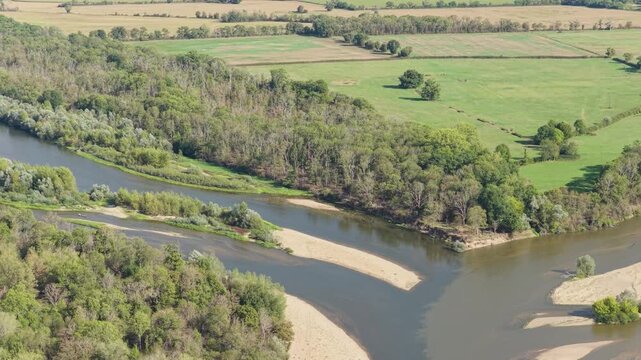 The Bec d'Allier in France, showing the confluence of rivers with winding water channels, sandbanks, and lush green forests, aerial view.
