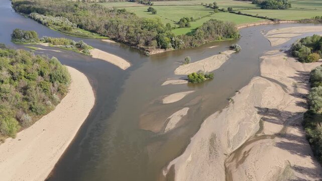 The Bec d'Allier in France, showing the confluence of rivers with wide sandy banks, green forested areas, and open fields, aerial view.
