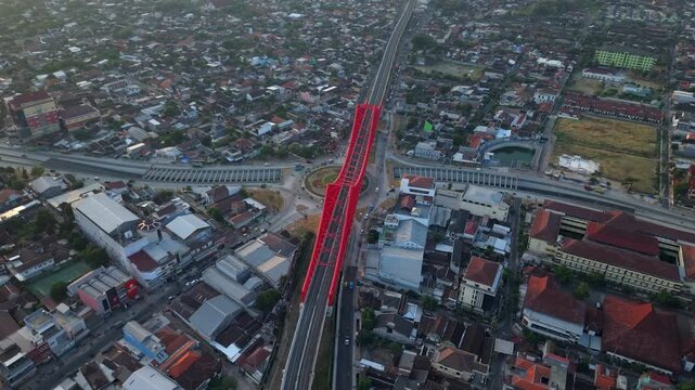 Aerial view of the red Joglo Railway Bridge crossing the city with surrounding rooftops and roads Kecamatan Banjarsari, Jawa Tengah, Indonesia.