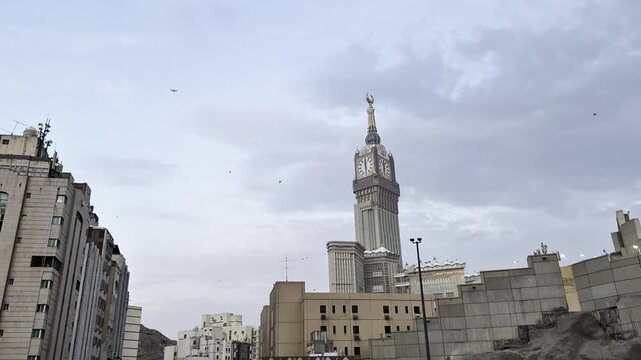 Makkah Clock Royal Tower surrounded by hotel buildings under cloudy sky in Mecca Saudi Arabia