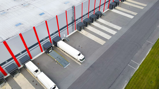 Large logistics center handling cargo with trucks backed into distribution doors, illustrating global supply chain operations and modern transportation infrastructure