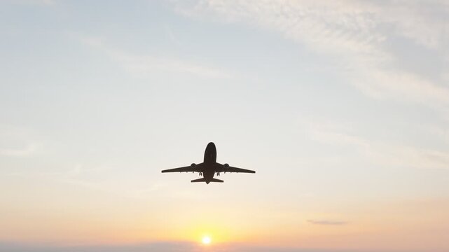 Commercial passenger airplane flying through a warm sunset sky, ideal for aviation, air travel, tourism, transportation, airline, and travel content.