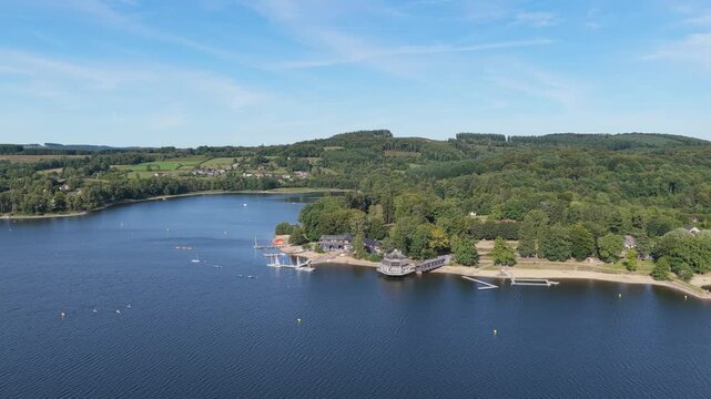 High-resolution aerial footage of Lac des Settons, a scenic lake surrounded by lush green forests and rolling hills in Morvan, Burgundy, France.