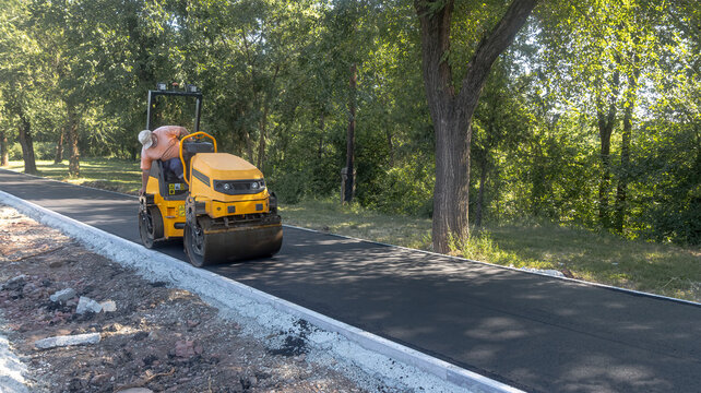 Small Road Roller Compacting Fresh Asphalt on New Path