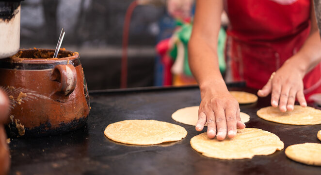 Person cooking corn tortillas on a hot griddle