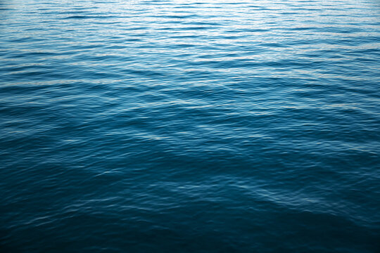Gently rippling sea water, showing smooth wave textures transitioning from deep turquoise in the foreground to soft light blue reflections near the horizon under natural daylight.