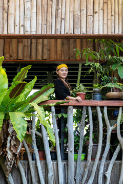 Malaysian indigenous Dayak woman standing at the balcony of wooden and bamboo house in a Lun Bawang traditional costume