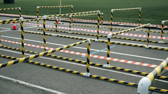 Outdoor obstacle course with striped barriers, safety tape and traffic cones arranged on a training ground for physical exercise and professional training.