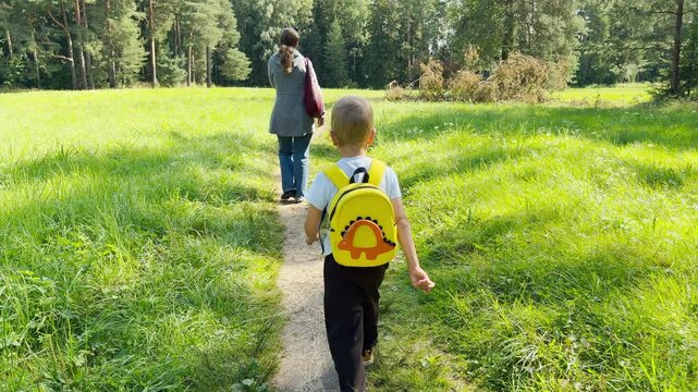 A mother and son walk along a trail through a lush green meadow. They feel happy and peaceful during this joyful outdoor stroll in the park.
