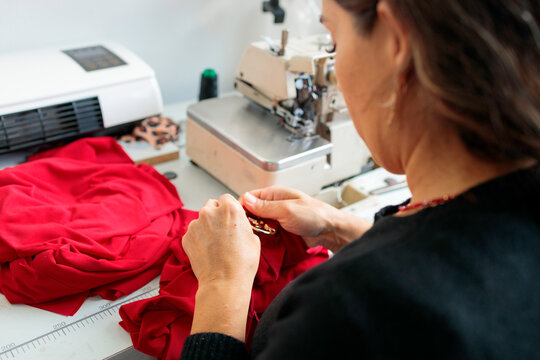 Woman hand stitching red garment