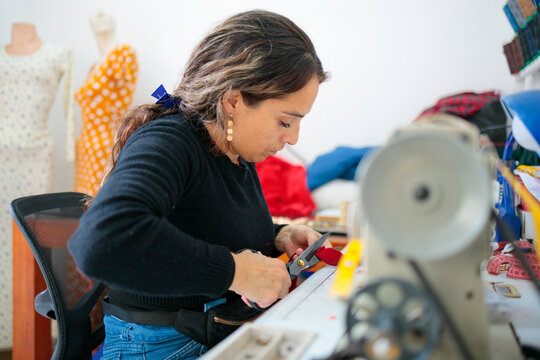 Woman cutting red fabric with scissors