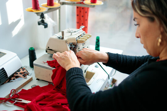 Woman hands sewing red textile fabric
