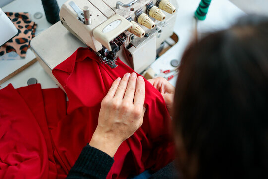 Woman tailoring red cloth on machine