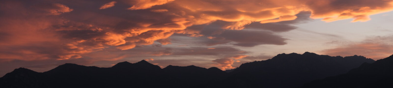 Panoramic fiery sunset clouds above mountains near Lake Garda