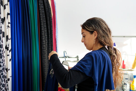 Woman inspecting garment and fabric in studio