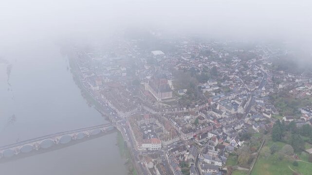 The city center of Gien, France, gradually enveloped by thick fog, aerial view.