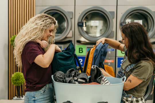 Friends sorting clothes in laundry basket at laundromat