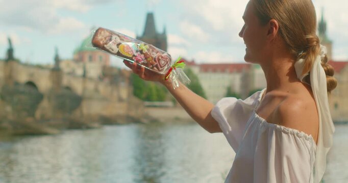 Smiling woman tourist holding a packaged assortment of traditional gingerbread cookies in Prague