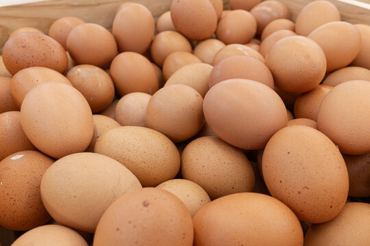 Abundant pile of fresh brown chicken eggs in rustic wooden crate natural light and wholesome organic food concept