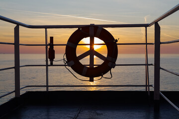 The silhouette of a lifebuoy aboard a ferry at sunset © marek_usz