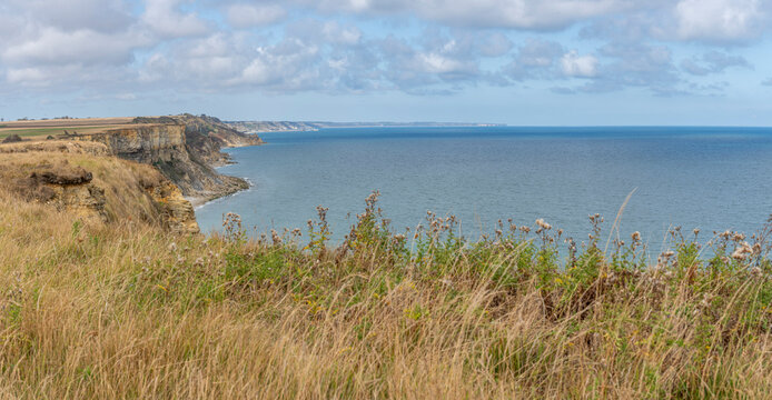 Arromanches-les-Bains, France - 08 10 2026: Coastal path. Panoramic view of the cliffs, the sea and cloudy sky from top of the path