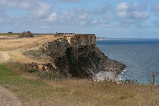 Arromanches-les-Bains, France - 08 10 2026: Coastal path. Panoramic view of the cliffs, the sea and cloudy sky from top of the path