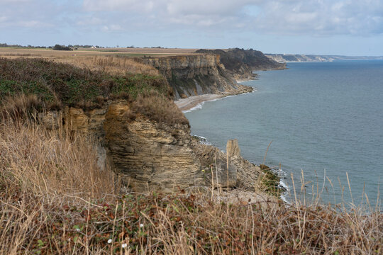 Arromanches-les-Bains, France - 08 10 2026: Coastal path. Panoramic view of the cliffs, the sea and cloudy sky from top of the path