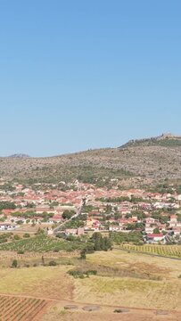The village of Opoul Perillos in southern France, framed by agricultural fields and rocky hills, aerial vertical 9:16 view.