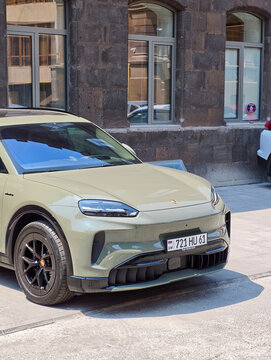Olive green electric vehicle parked outside urban building with arched windows