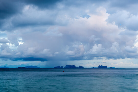 Koh Kradan Island in Thailand. Distant view of tropical island under cloudy sky. Calm turquoise sea with overcast weather. Scenic landscape of Andaman Sea coast.
