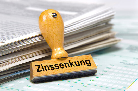 Ein Holzstempel ist bedruckt mit der Aufschrift: Zinssenkung