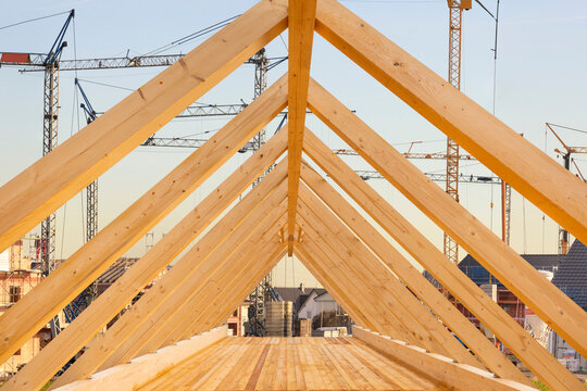 Auf dem Dach von einem Wohnhaus wird von einem Zimmermann der Dachstuhl mit Holzbalken gebaut - FOTOMONTAGE